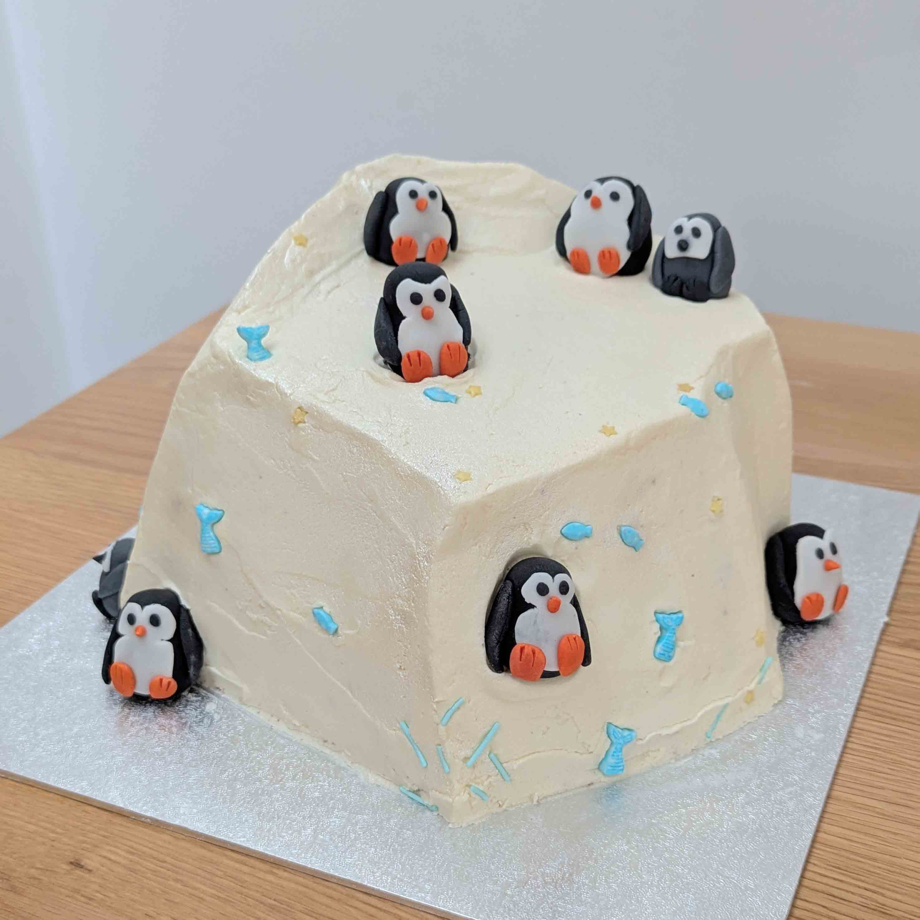 Iceberg-shaped cake decorated with fondant penguins, fish and stars