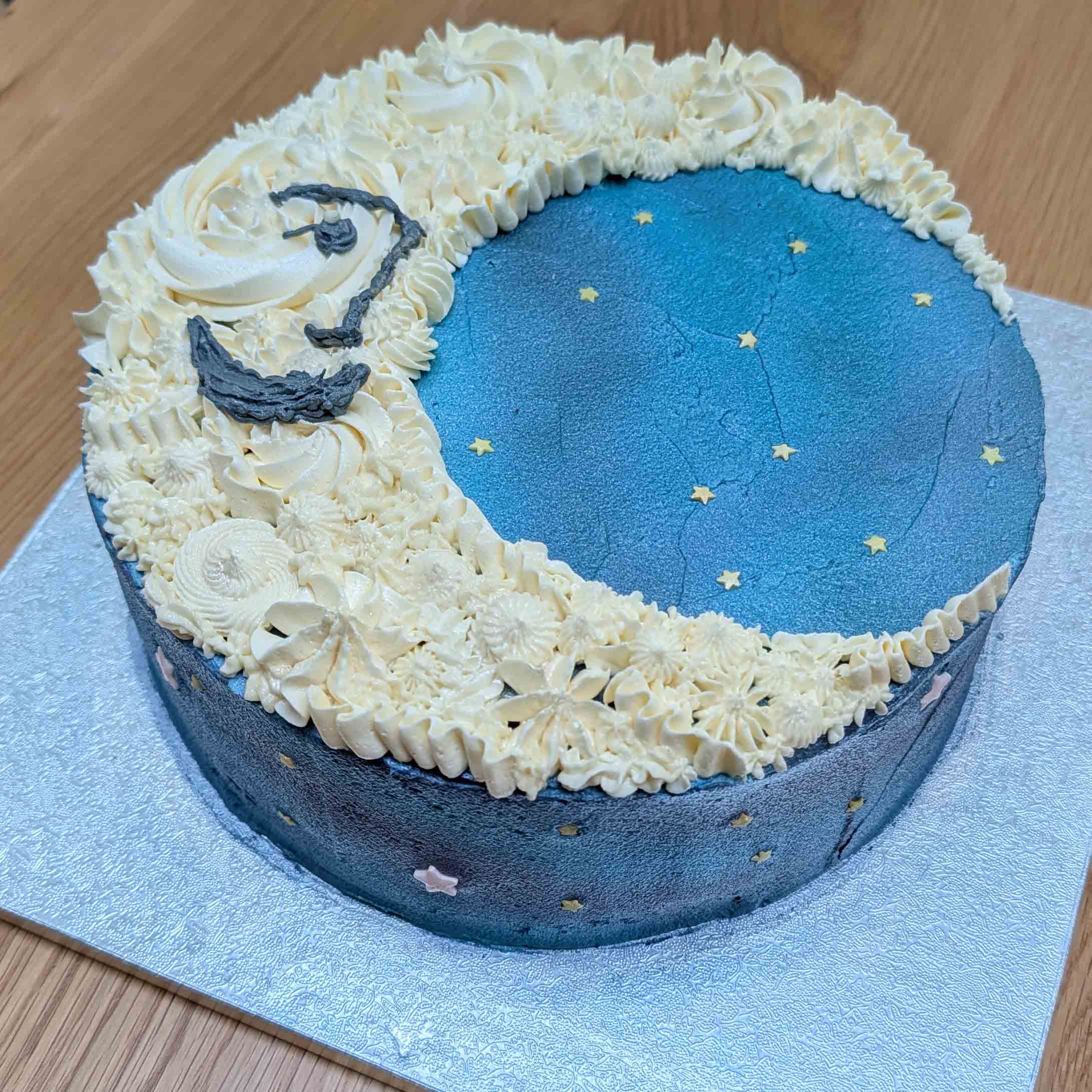 Crescent moon and starry night sky cake with piped buttercream cloud swirls